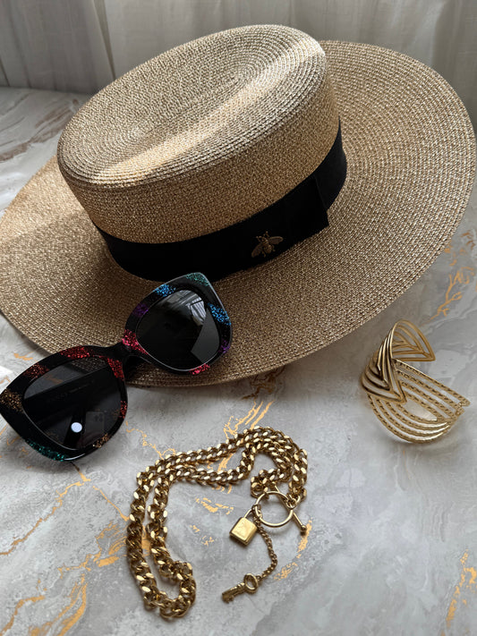 Gucci gold metallic boater hat with bee appliqué, colorful sunglasses, gold chain necklace and cuff on marble surface — Shimmer & Shawls Summer Accessories Edit