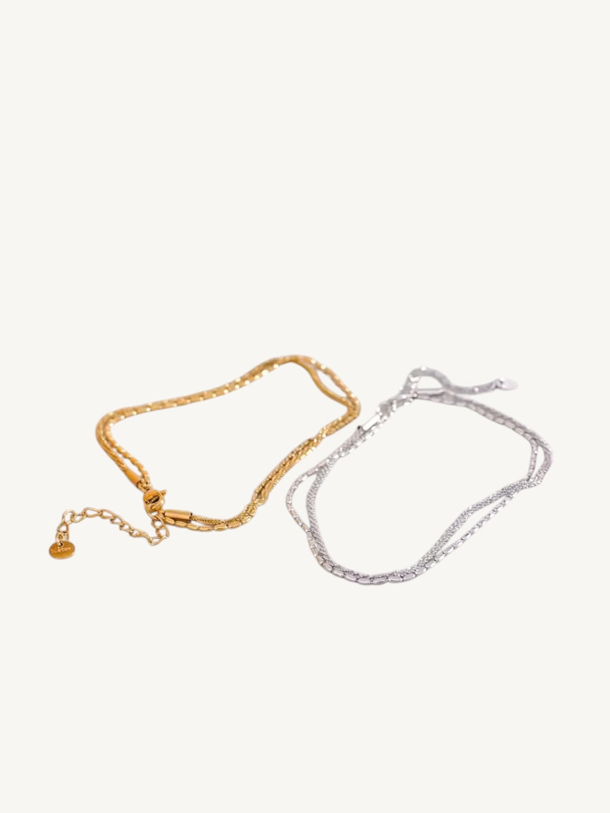 The Côte gold and silver double-strand chain anklets side by side flat lay — Shimmer & Shawls