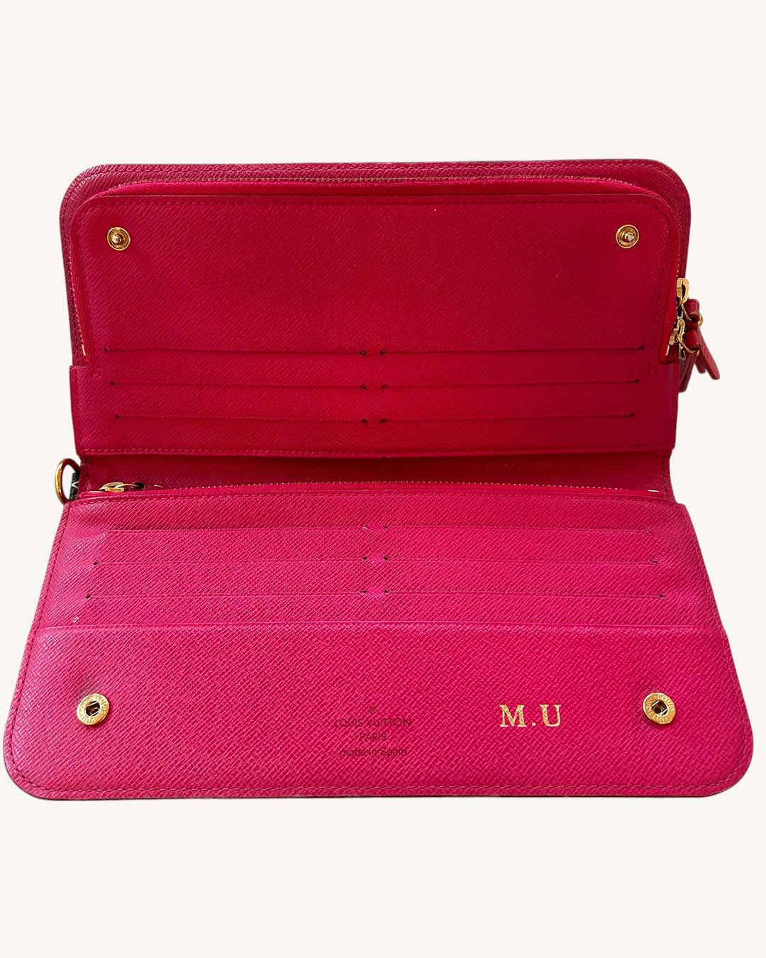 Louis Vuitton Insolite wallet opened to show pink leather card slots, gold-tone snaps and M.U personalization.