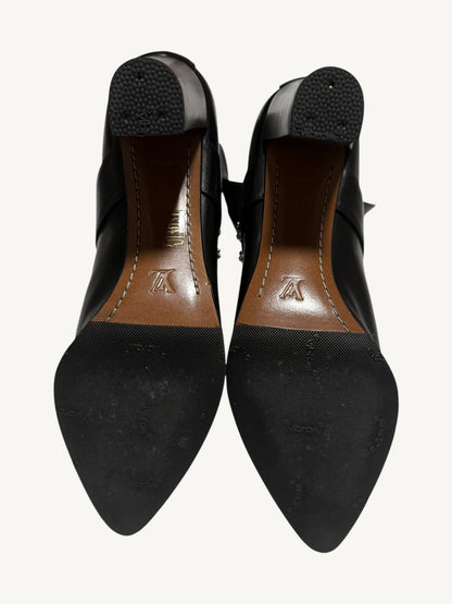 Soles of both Louis Vuitton boots, showing black rubber half-soles, textured heel caps and brown leather arches.