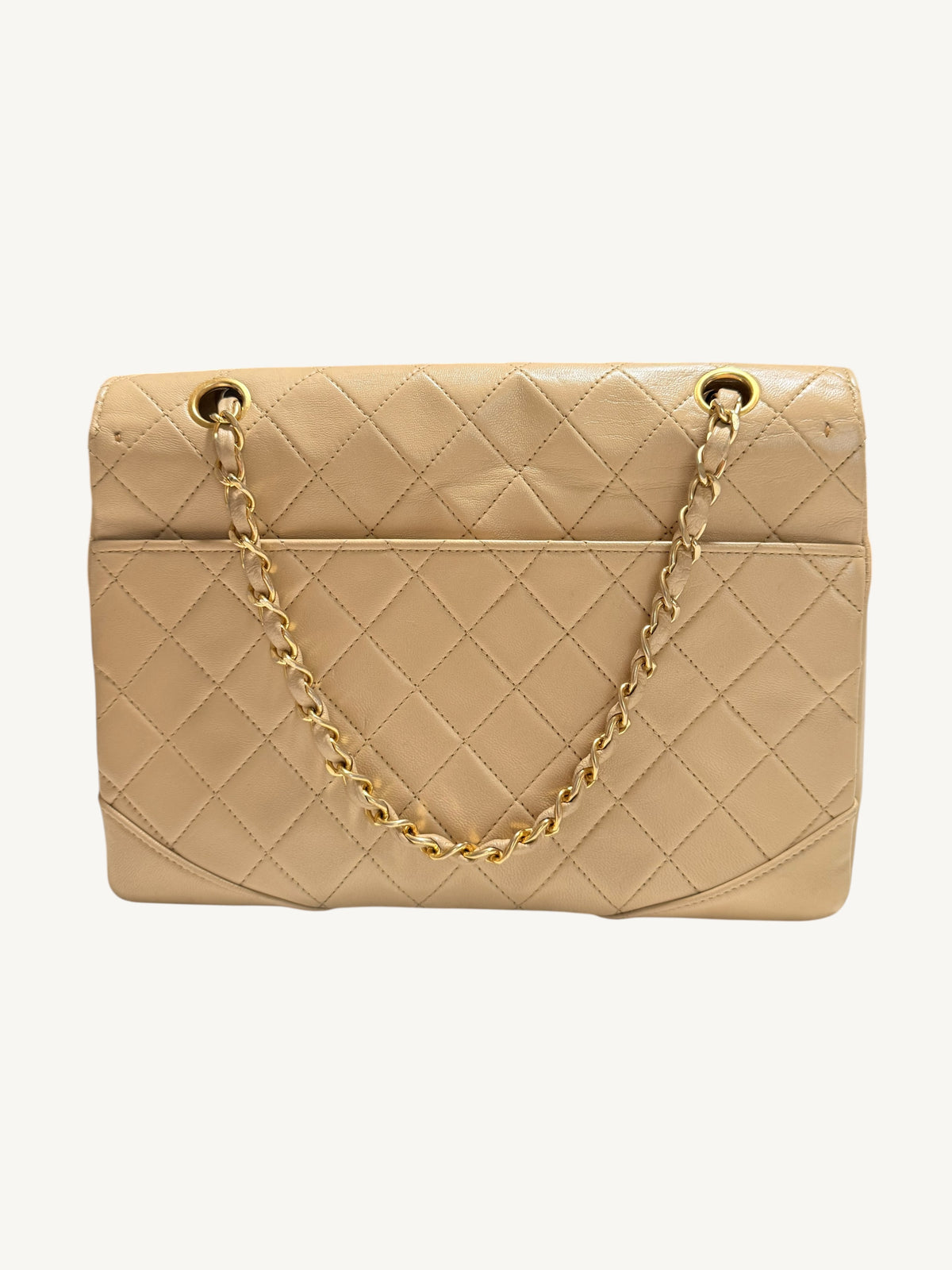 A beige quilted leather Chanel handbag with a gold-tone chain strap and gold-tone hardware, shown against a plain off-white background.