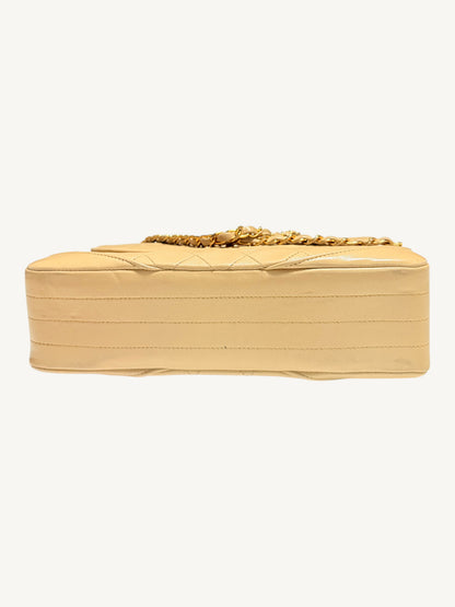 A light beige quilted leather Chanel bag with a gold chain strap, shown from the side against a plain off-white background.