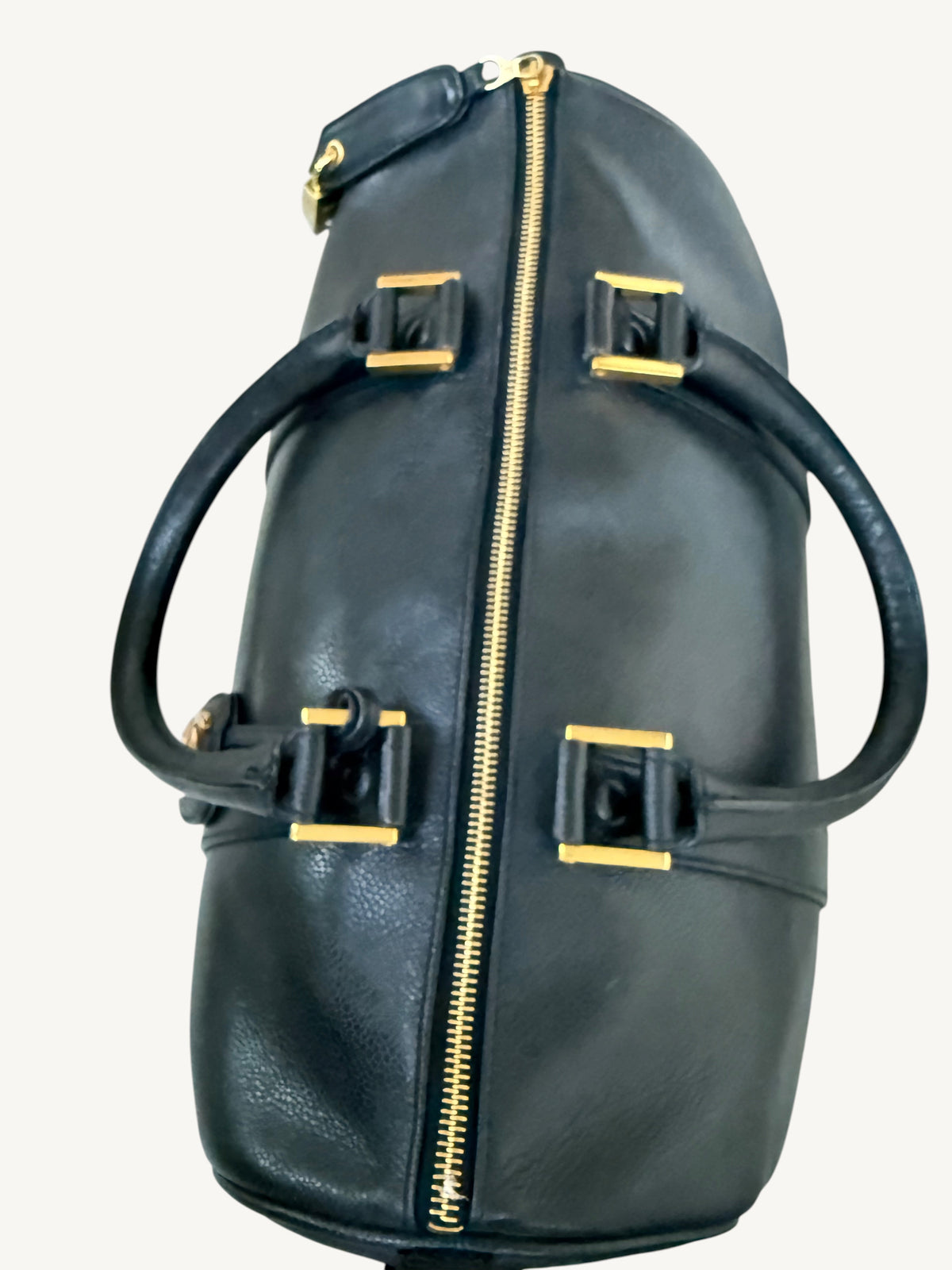 A black CHANEL leather cylindrical duffel bag with gold-tone hardware, featuring two top handles and a central zipper closure, shown against a plain light background.