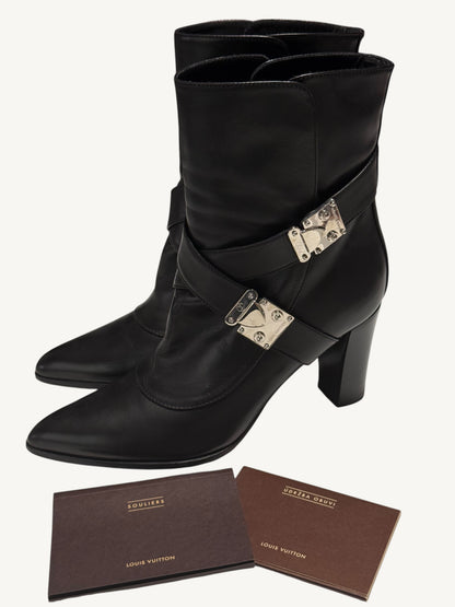 Black Louis Vuitton S-Lock ankle boots displayed with two brown Louis Vuitton booklets.