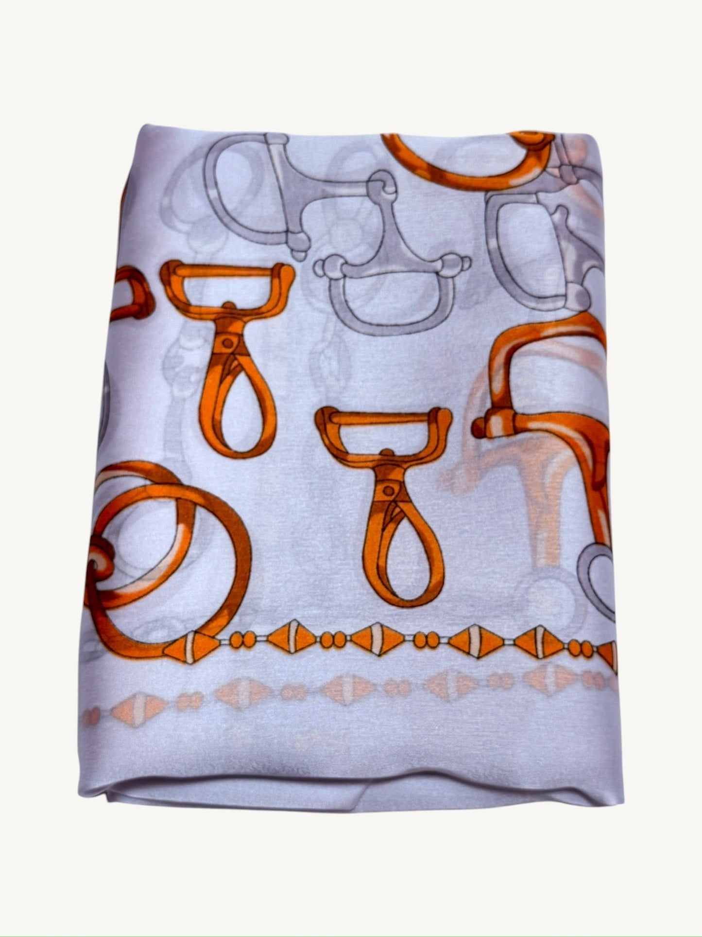 The Deauville – equestrian print silky satin scarf folded showing white base with orange hardware motifs