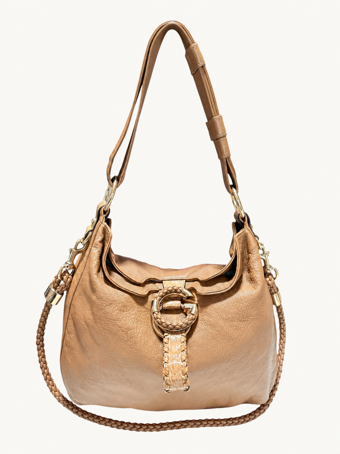 A camel brown Gucci leather shoulder bag with a large circular G gold-tone front harware, a woven strap detail, and a braided shoulder strap, shown against a plain off-white background.