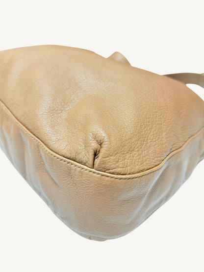 A close-up of a camel brown Gucci  leather shoulder bag showing the pebbled texture and stitching details against a plain white background.
