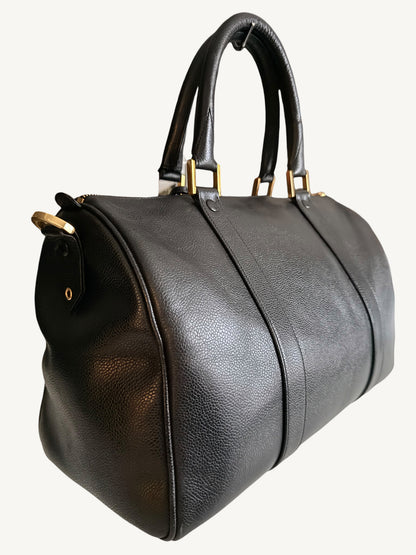 A black pebbled leather CHANEL duffel bag with double top handles and gold-tone hardware, shown against a plain off-white background.