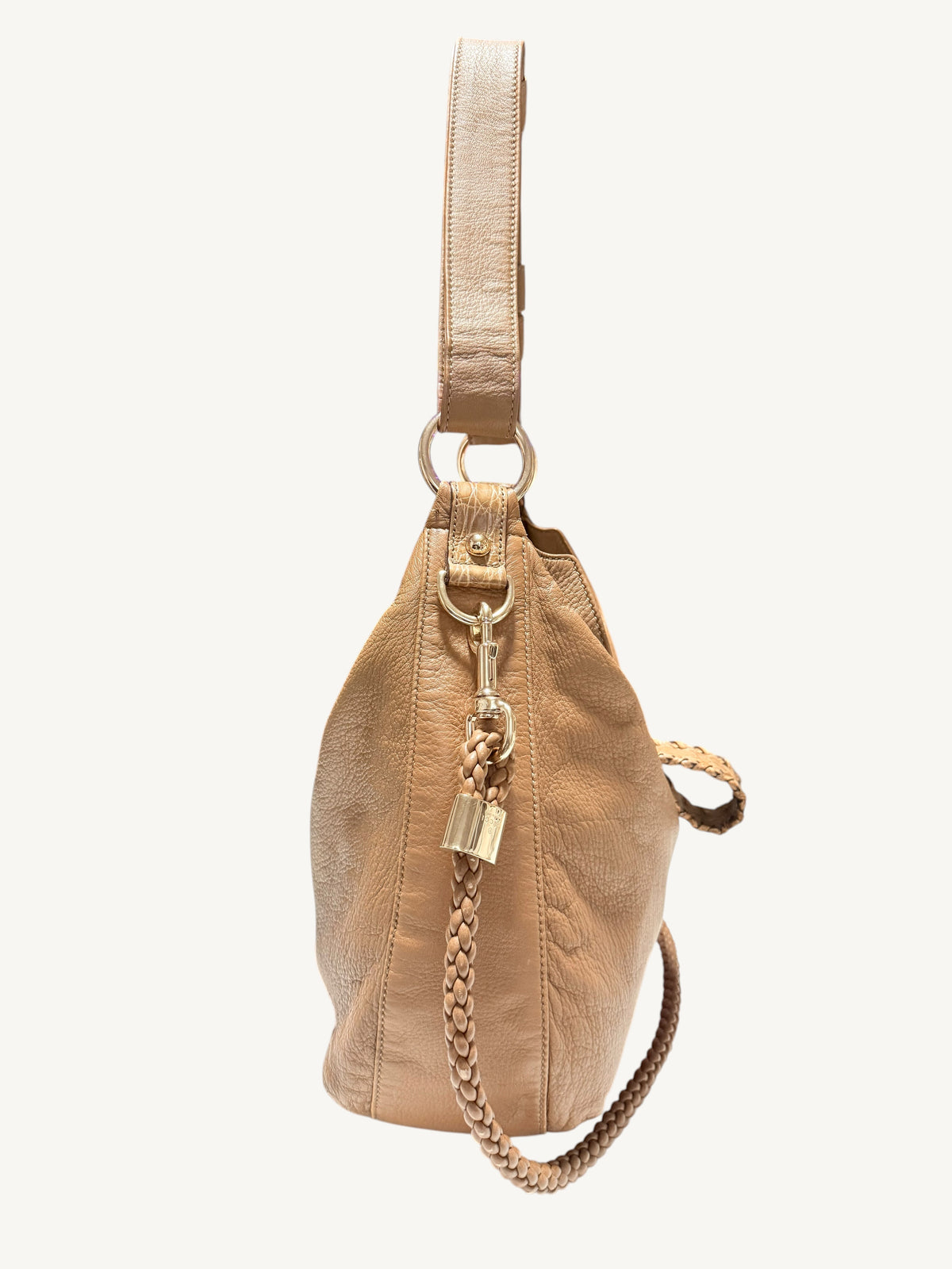 A camel brown Gucci leather bucket bag with a matching shoulder strap, gold-tone hardware, and a braided chain detail, shown against a plain off-white background.