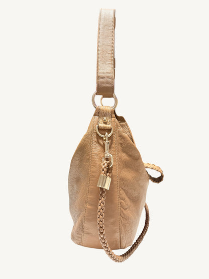 A camel brown Gucci leather bucket bag with a matching shoulder strap, gold-tone hardware, and a braided chain detail, shown against a plain off-white background.