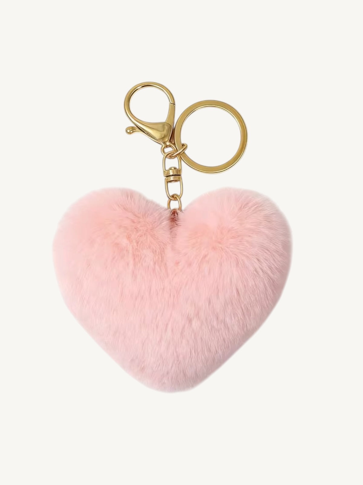 A light pink faux fur heart-shaped keychain with a gold-tone lobster clasp and split key ring, shown on a plain off-white background.