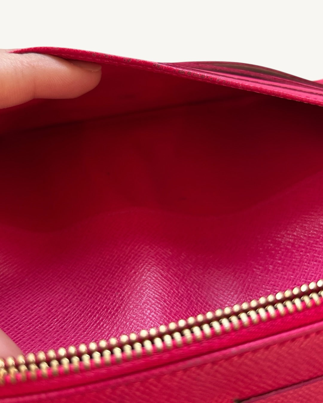 Close-up inside the Louis Vuitton Insolite wallet's pink leather zip pocket showing minor coin residue.