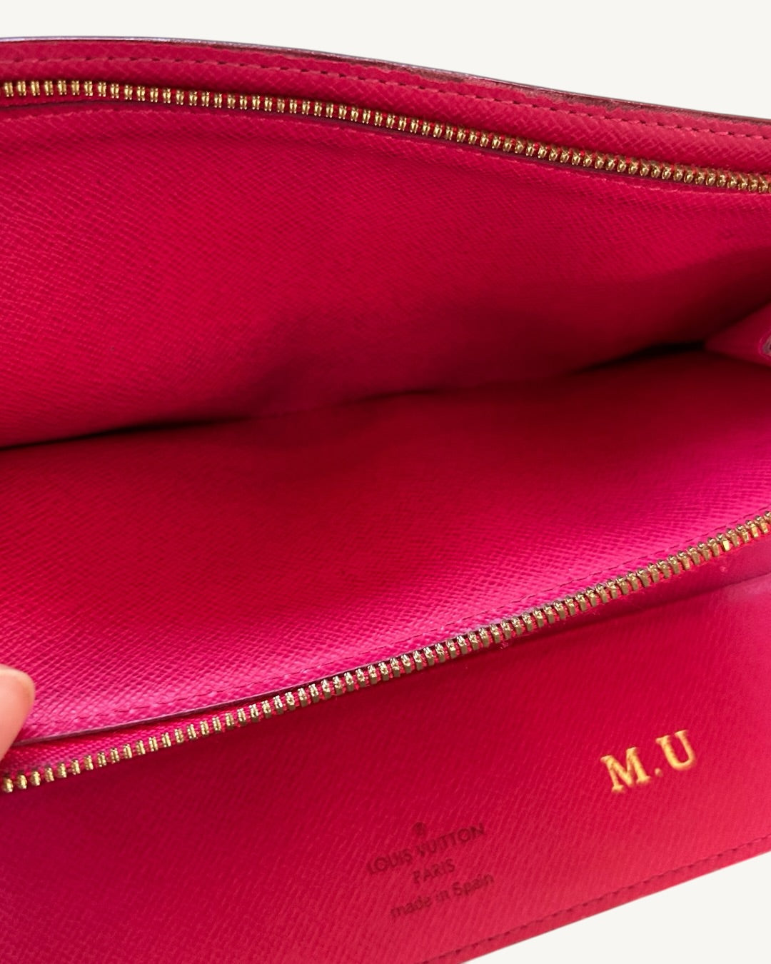 Open pink leather compartment with gold-tone zipper, Louis Vuitton Made in Spain stamp and gold-foil M.U initials.
