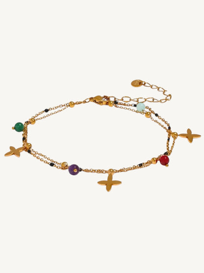 A gold-toned double-strand chain anklet featuring starfish charms, small colorful beads in green, purple, red, and light blue, and a lobster clasp on a light cream background.