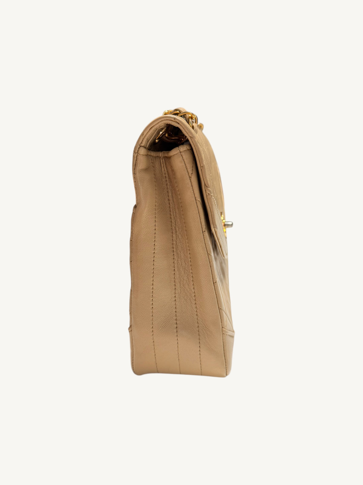 A side profile view of a beige Chanel leather handbag with gold-tone hardware, shown against a plain off-white background.