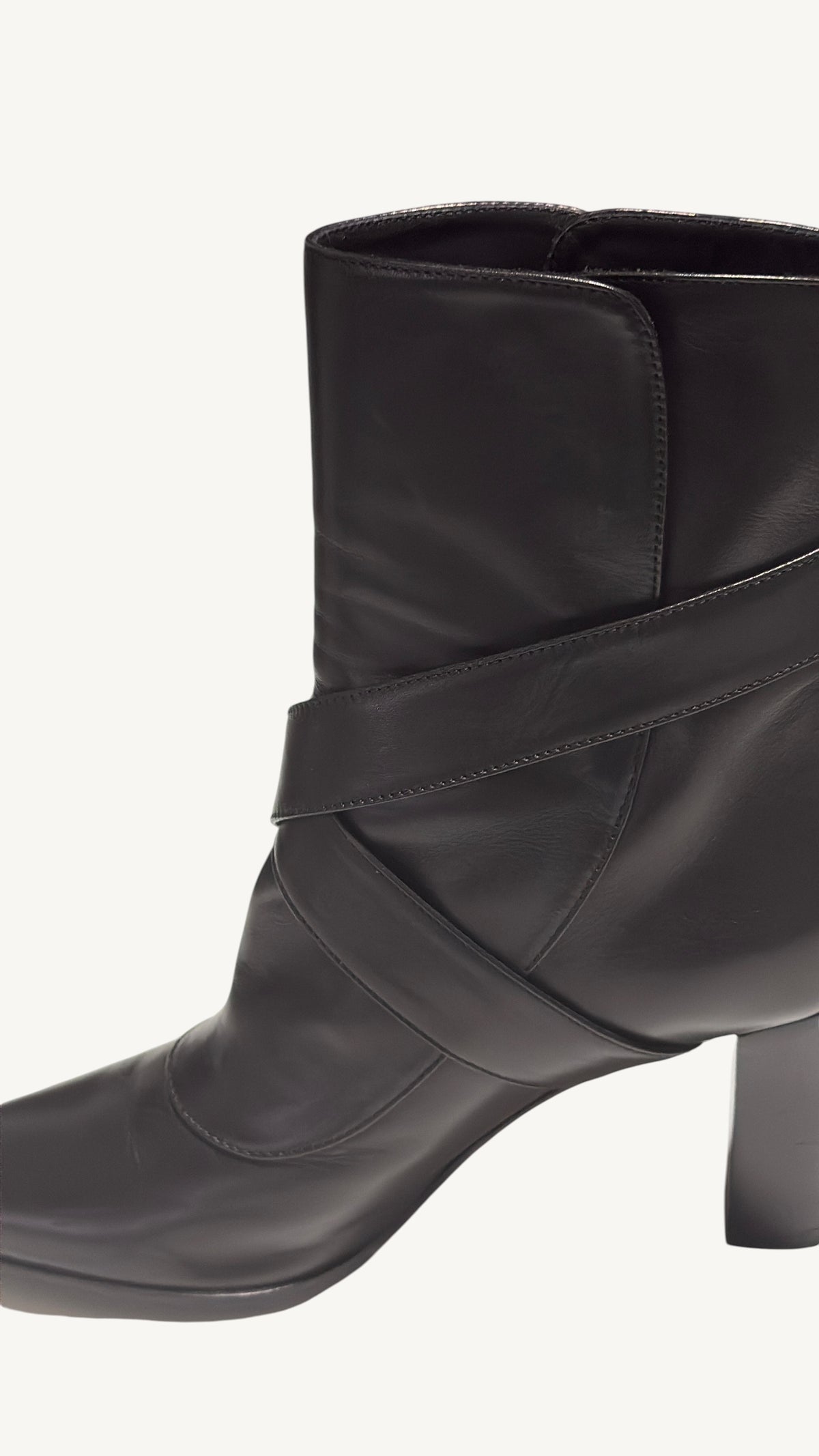 Close-up of overlapping black leather straps, stitching and ankle creasing on a Louis Vuitton boot.