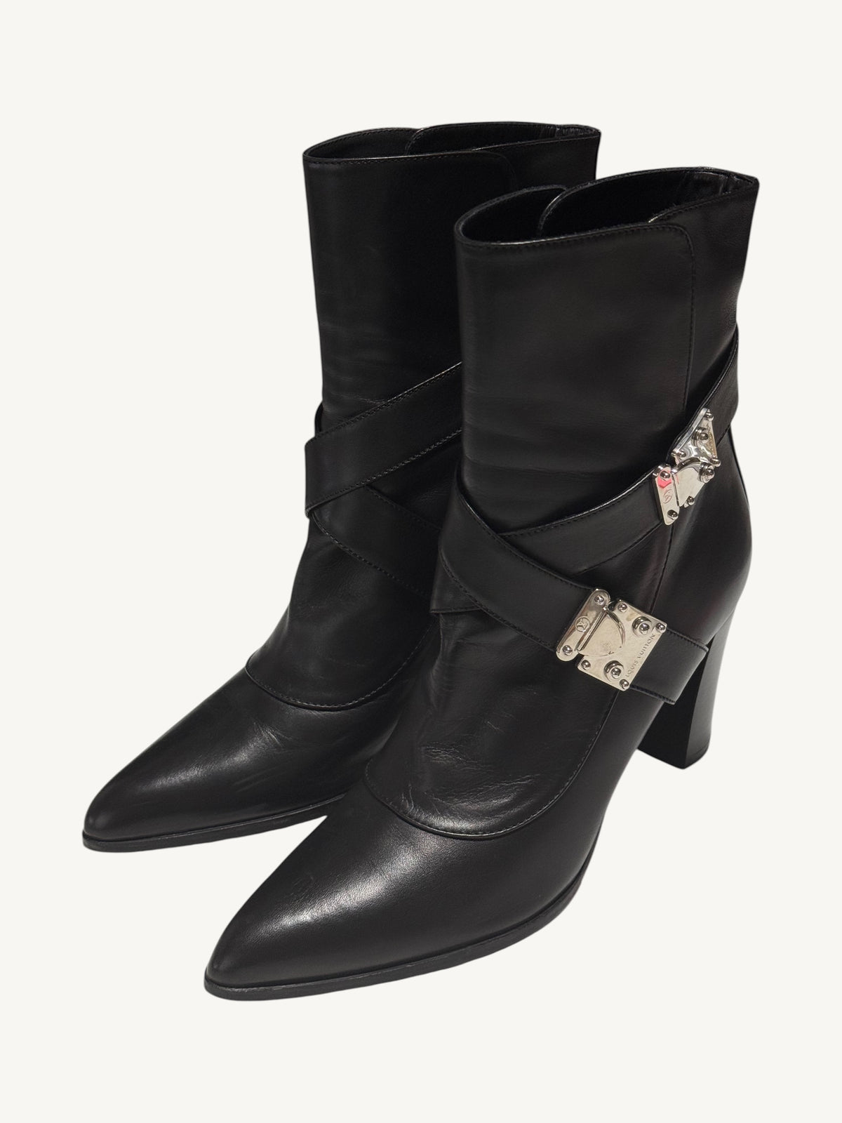 Black Louis Vuitton ankle boots angled left, showing pointed toes, crossed straps and silver-tone clasps.
