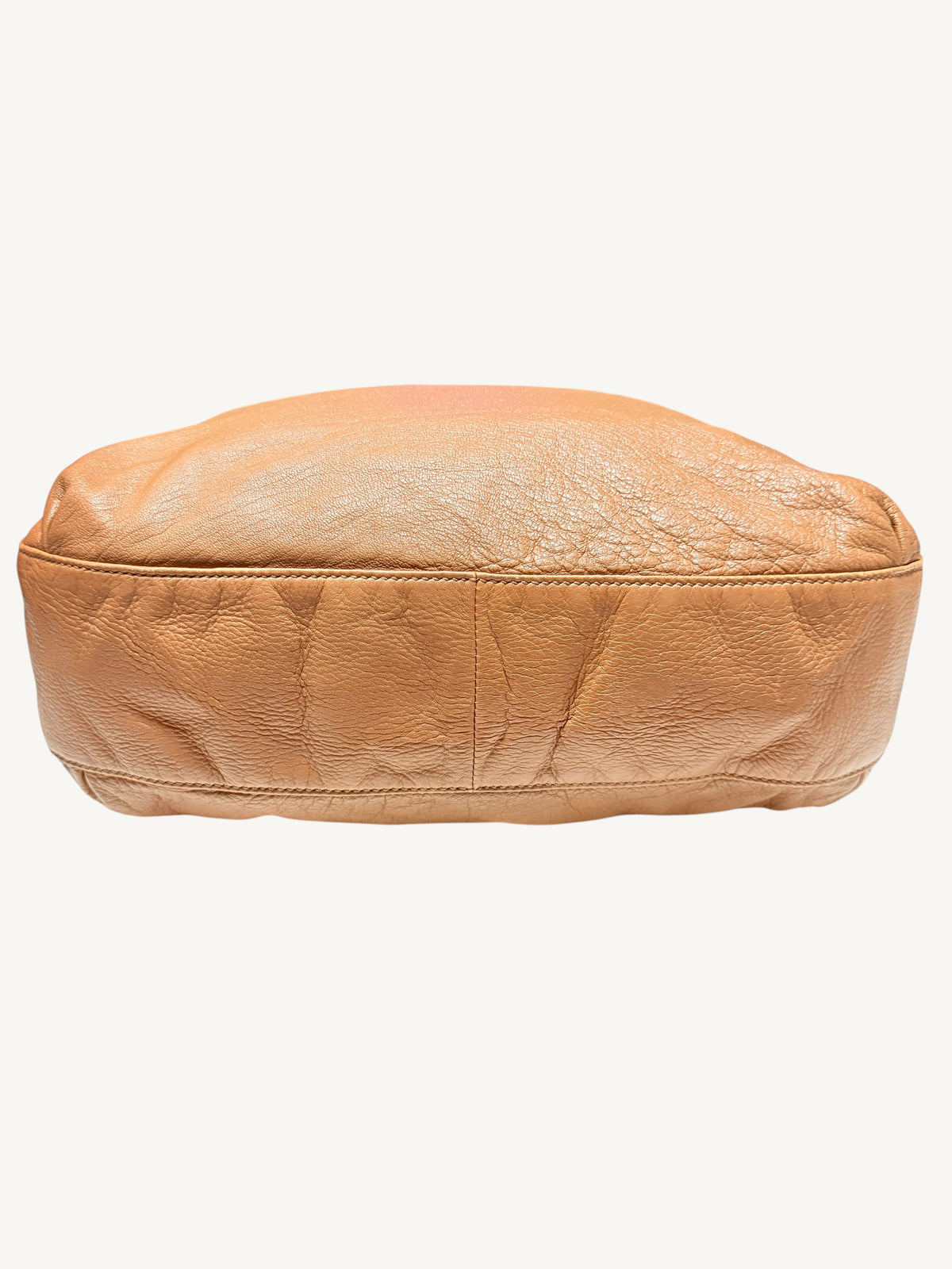 The bottom of camel brown Gucci leather  shown against a plain off-white background.