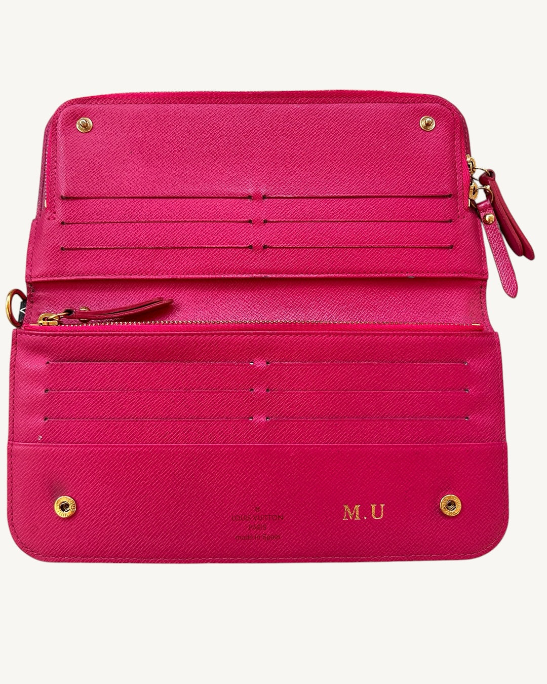 Flat-open Louis Vuitton Insolite wallet with Grenade pink interior, 12 card slots, zipper and gold-foil M.U initials.