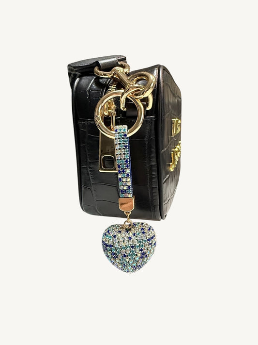 A black crocodile-embossed leather keychain bag with gold hardware, featuring a rhinestone-embellished wrist strap and a dangling heart-shaped charm, shown against a plain off-white background.
