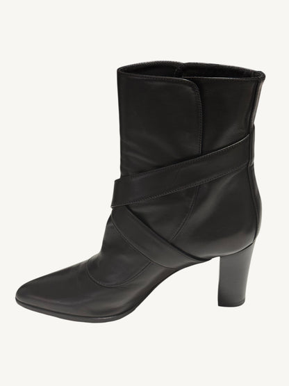Side profile of a black Louis Vuitton ankle boot, showing crossed leather straps and a block heel.