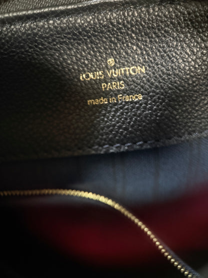Close-up of a black textured leather Louis Vuitton interior with gold foil stamping reading 'LOUIS VUITTON PARIS made in France' and a gold zipper visible along the bottom.