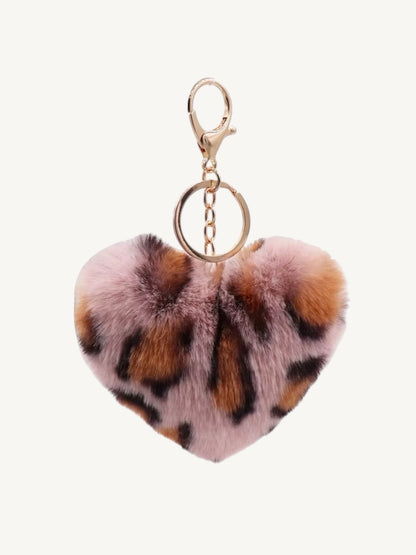 A heart-shaped faux fur keychain with a pink, brown, and black leopard print pattern, attached to a gold-tone lobster clasp and split ring, shown against a plain off-white background.