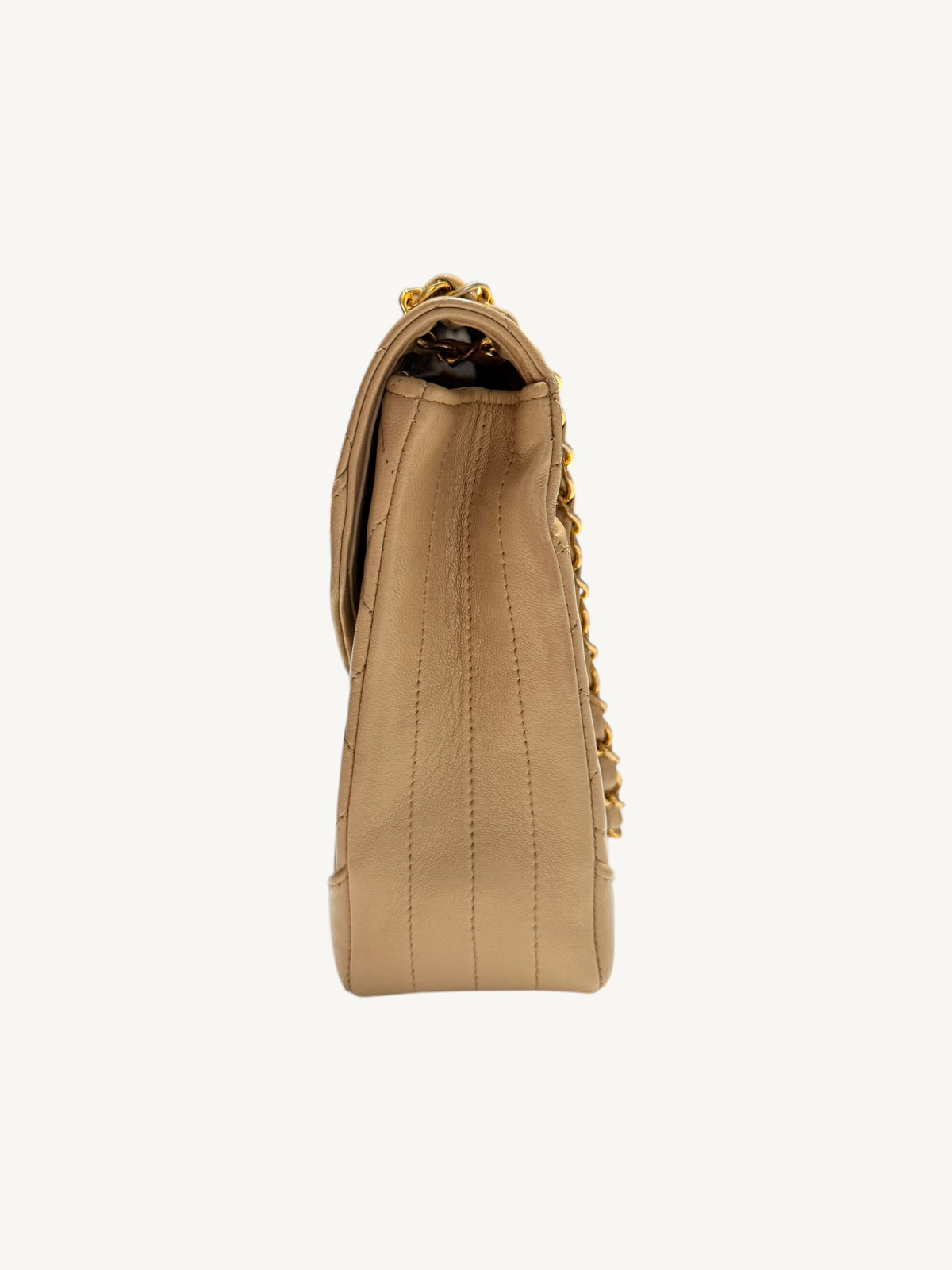 A side profile view of a beige Chanel leather shoulder bag with gold-tone chain detailing, shown against a plain off-white background.