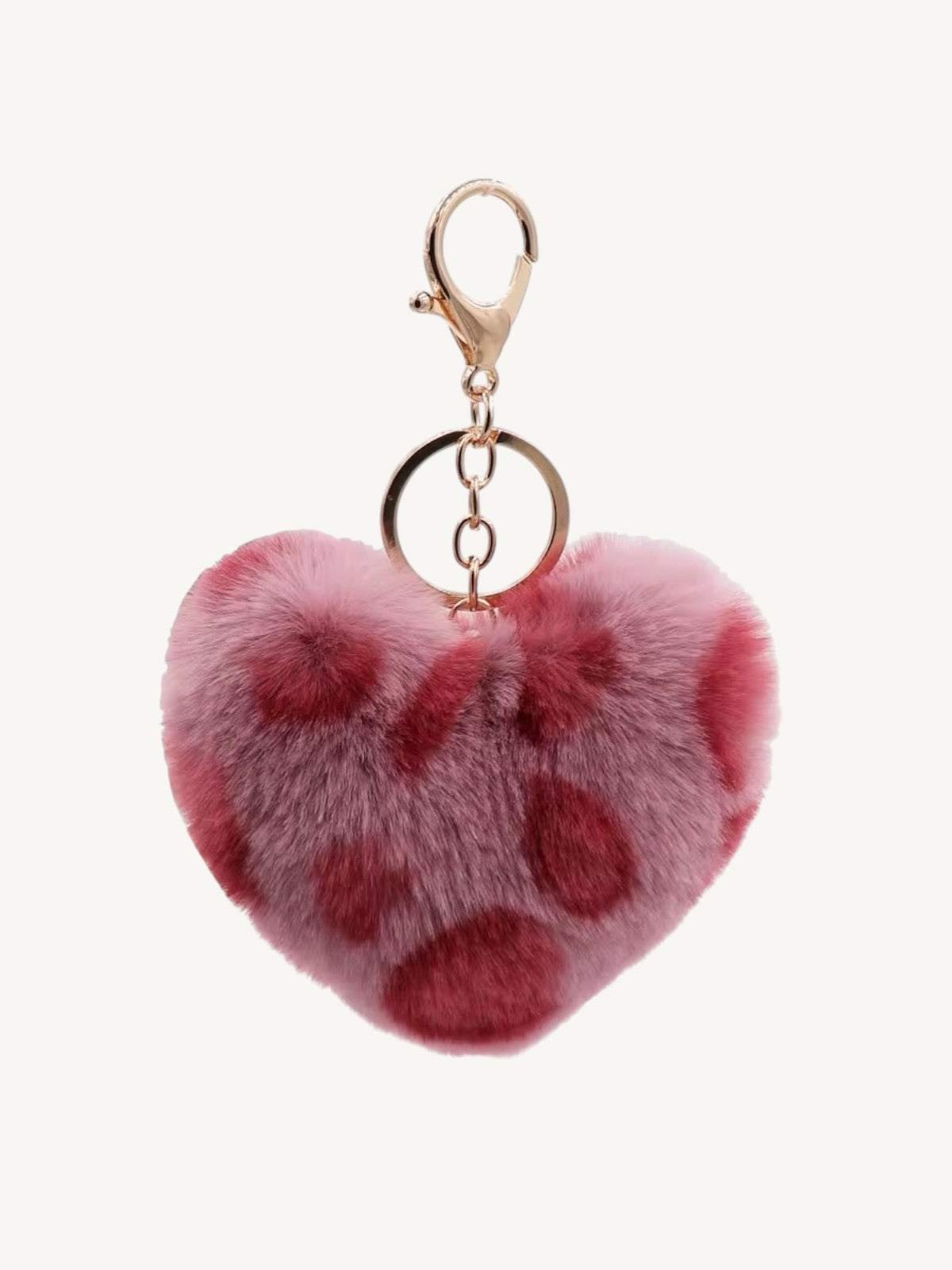 A pink faux fur heart-shaped keychain with dark pink spots, attached to a gold-tone lobster clasp and split ring, shown against a plain off-white background.