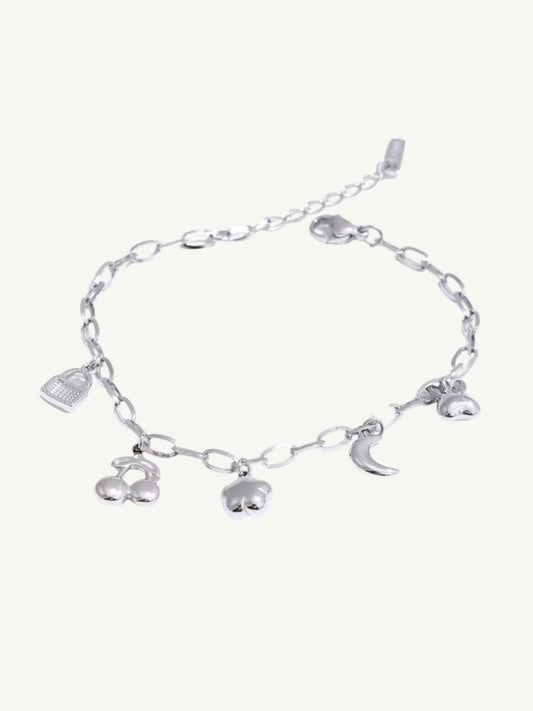 A silver chain bracelet with dangling charms including a small bird, a crescent moon, and two cherub figures, displayed on a light cream background.