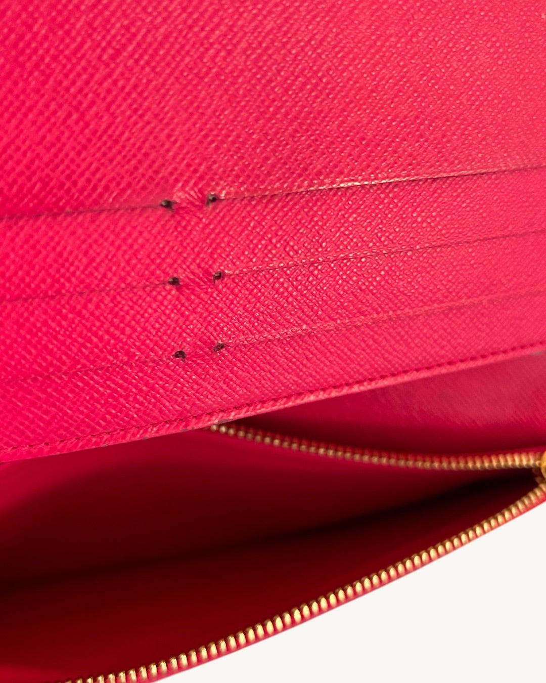 Close-up of Grenade pink leather card slots and an open zip compartment in the Louis Vuitton Insolite wallet.