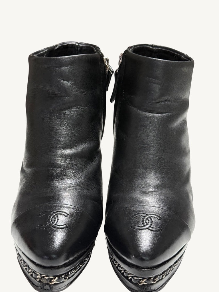 Close front view of Chanel vintage black ankle boots showing embroidered CC toes and chain platforms