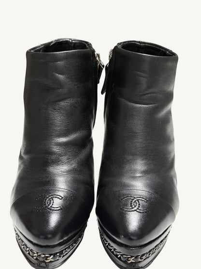 Close front view of Chanel vintage black ankle boots showing embroidered CC toes and chain platforms