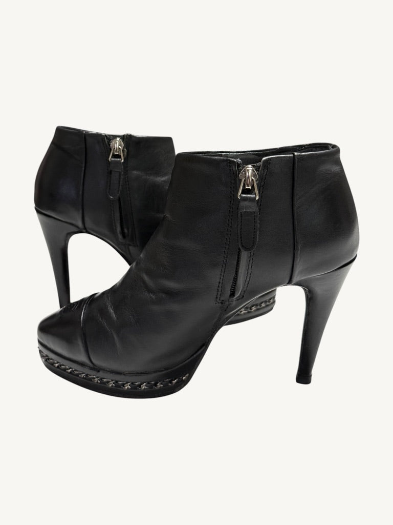 Chanel vintage black calfskin ankle boots showing interior side zippers, chain platforms and stiletto heels