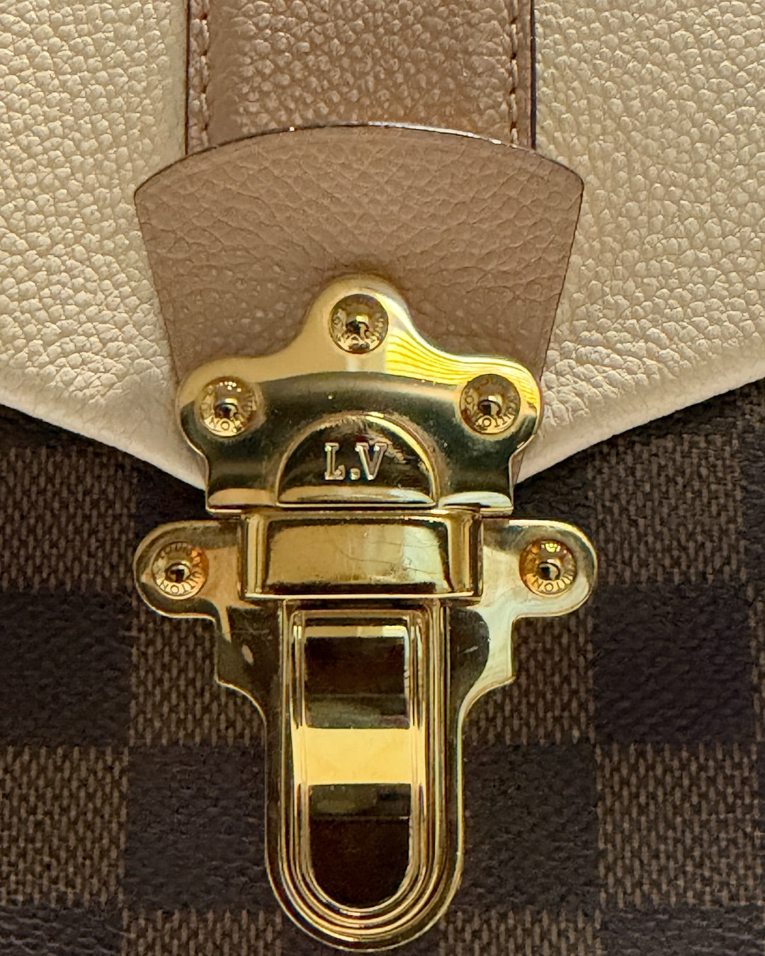 Louis Vuitton Clapton Backpack — Close-up of LV-engraved gold-tone clasp and warm taupe leather tab