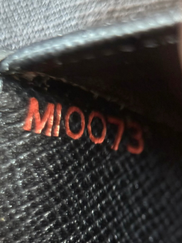 Close-up of MI0073 date code stamped inside Louis Vuitton black leather wallet