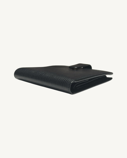 Side angle of closed Louis Vuitton black Epi wallet showing folded leather edges