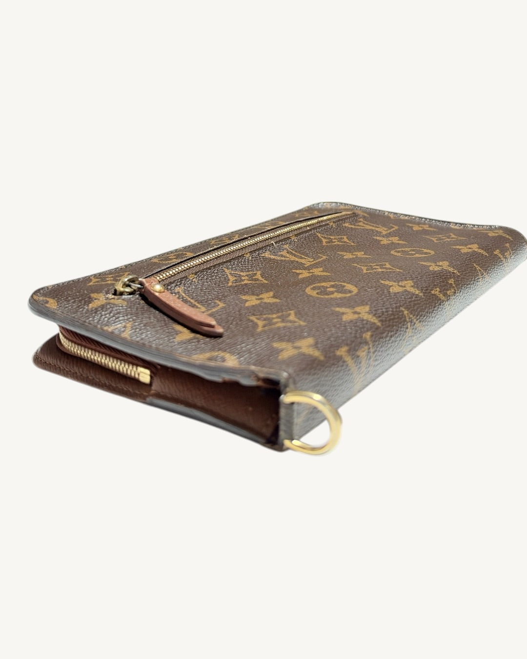 Three-quarter view of brown Monogram wallet with D-ring in foreground and leather zip pull
