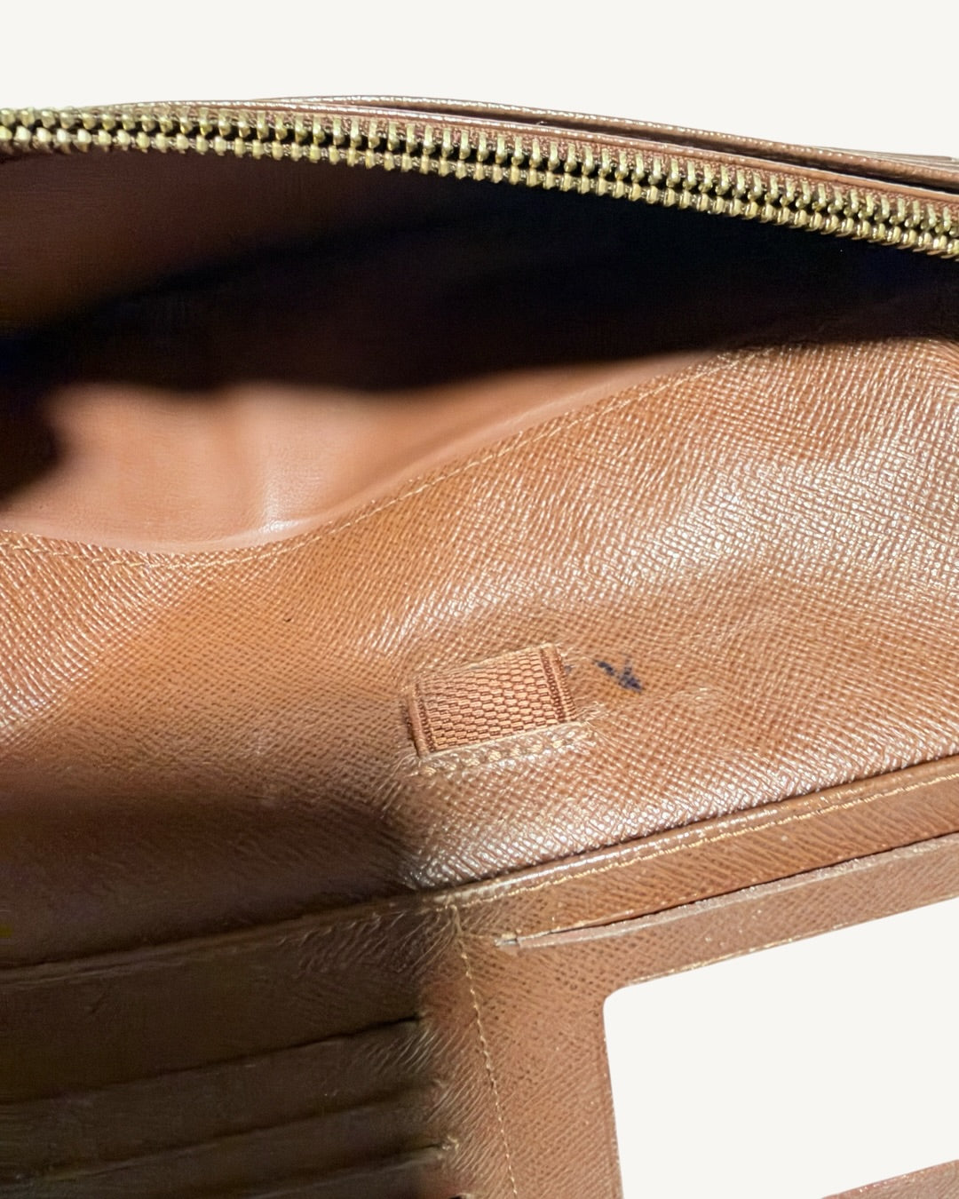 Close-up of small localized ink marks beside central pen loop with zippered pocket opened