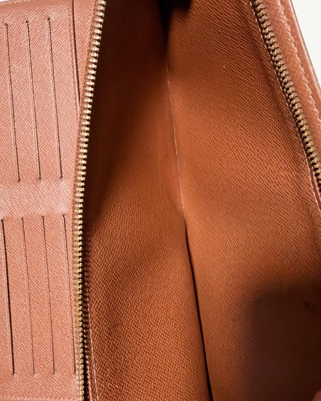 Open interior zippered compartment showing brown lining and adjoining card slots