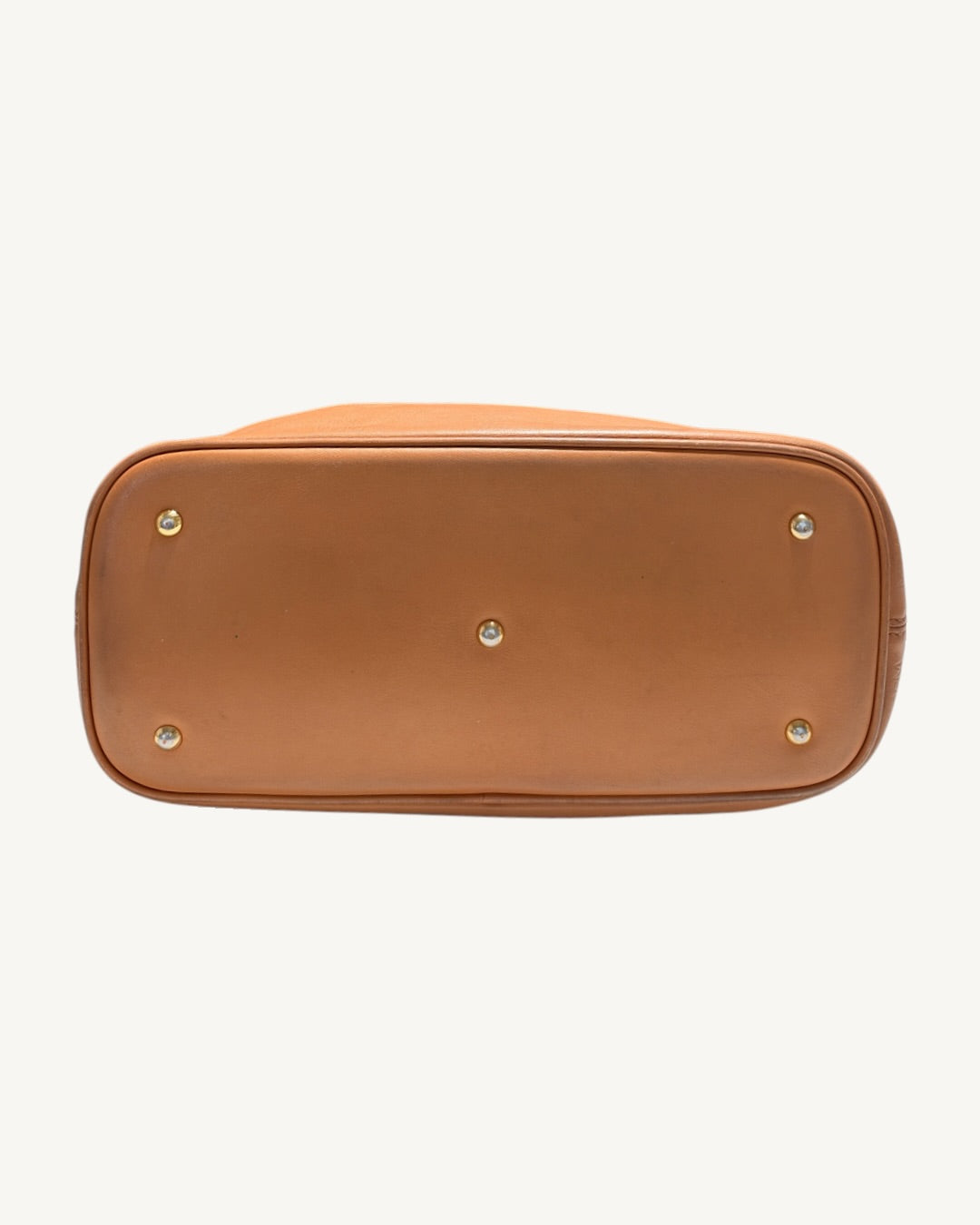 Straight-on view of the MCM tote leather base with five protective metal feet and perimeter piping.