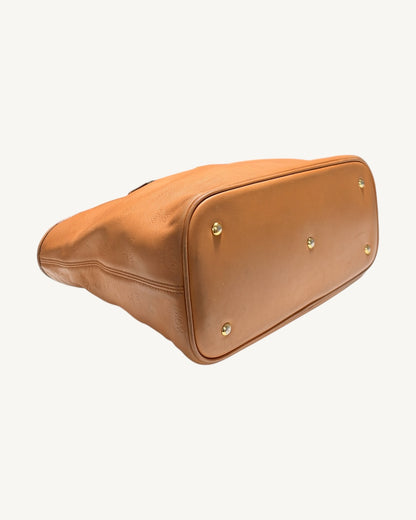 MCM tote underside angled from the opposite end, showing the leather base and five metal feet.