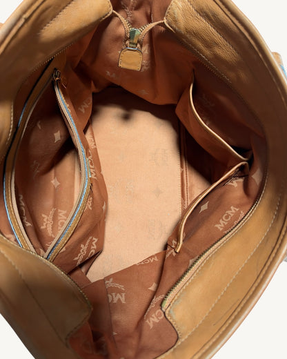 Open MCM tote interior showing fabric lining, base discoloration, one zip pocket and two slip pockets.