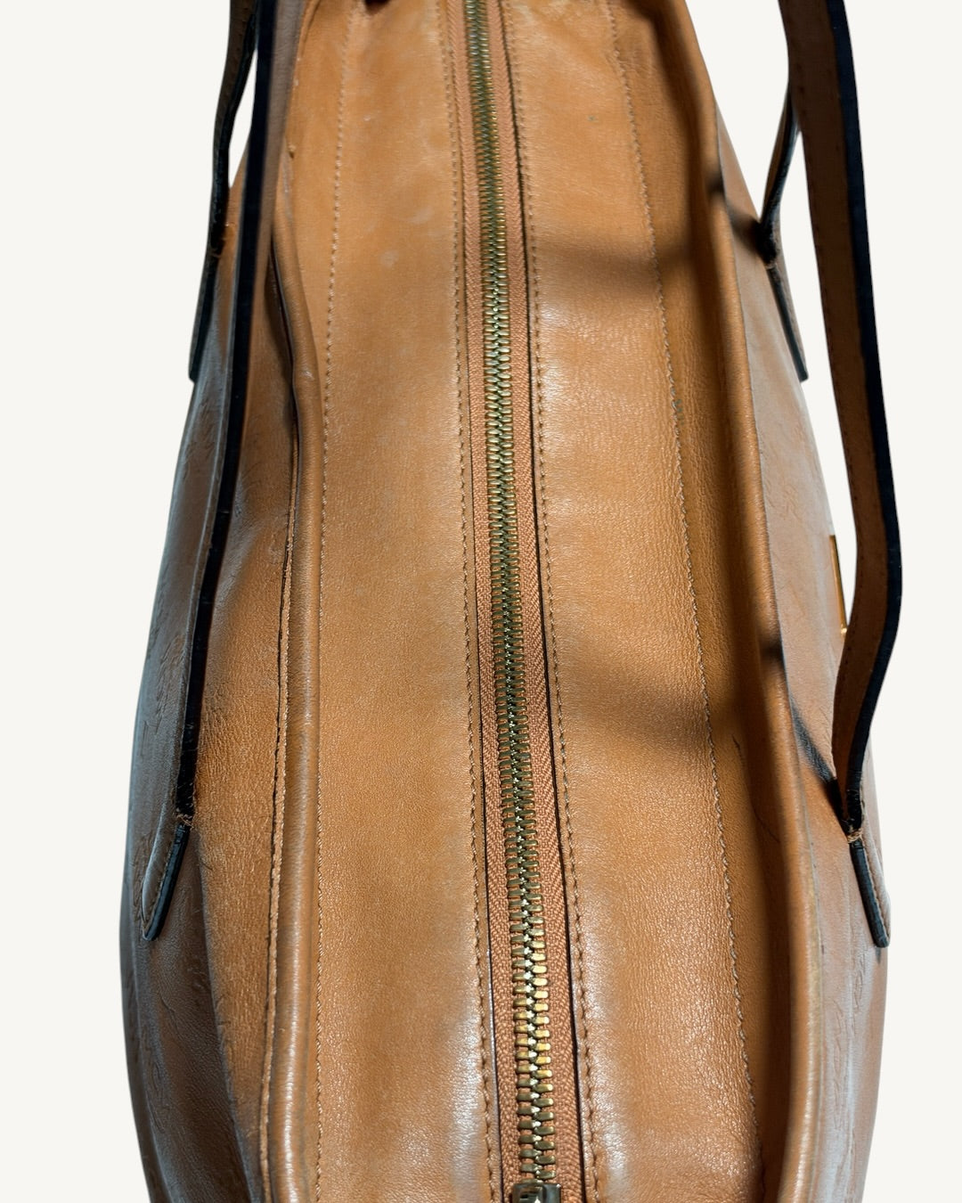 Close-up along the MCM tote gold-tone top zipper showing stitching and uneven coloration of leather trim.